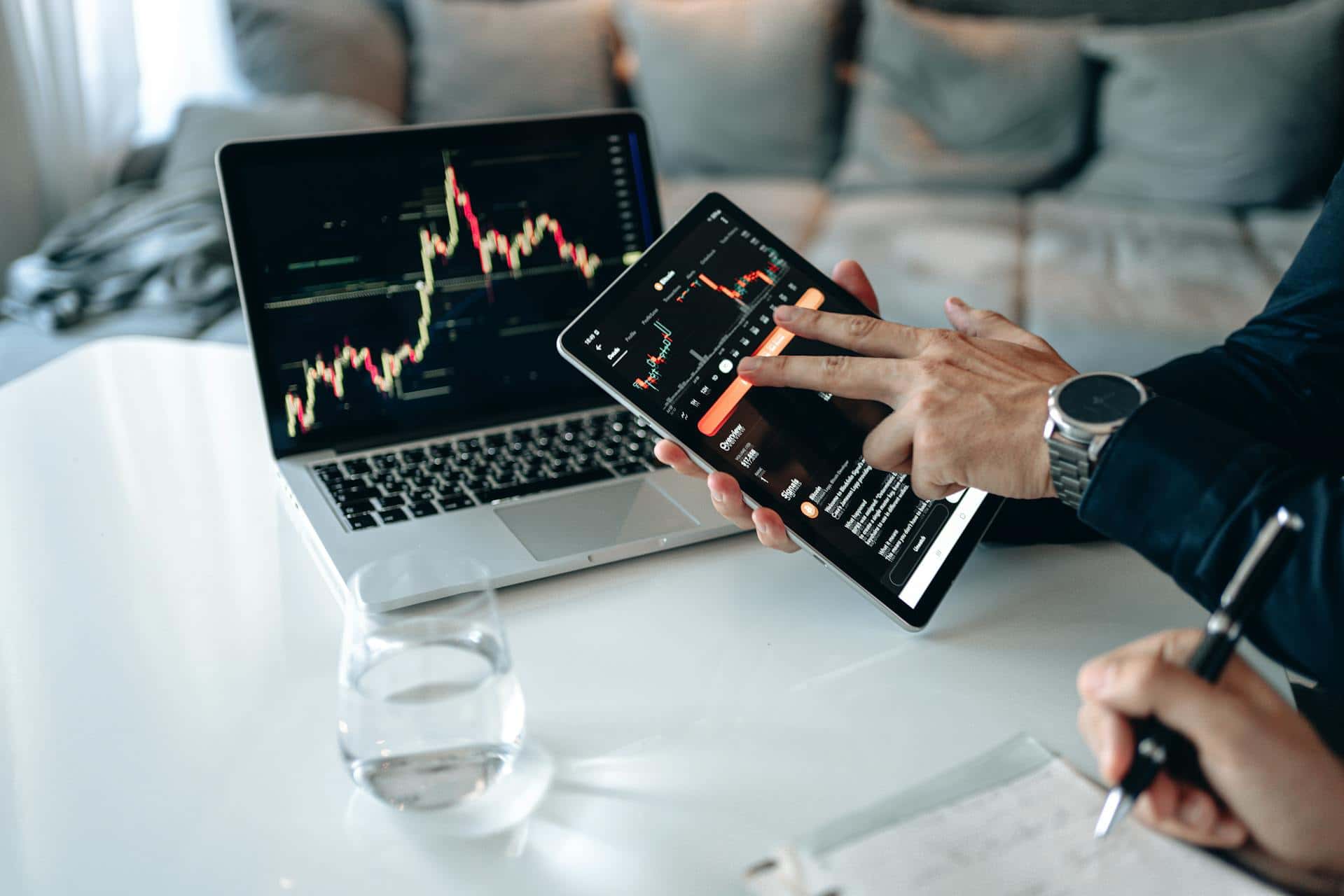 A trader analyzing stock market charts on a laptop and tablet.